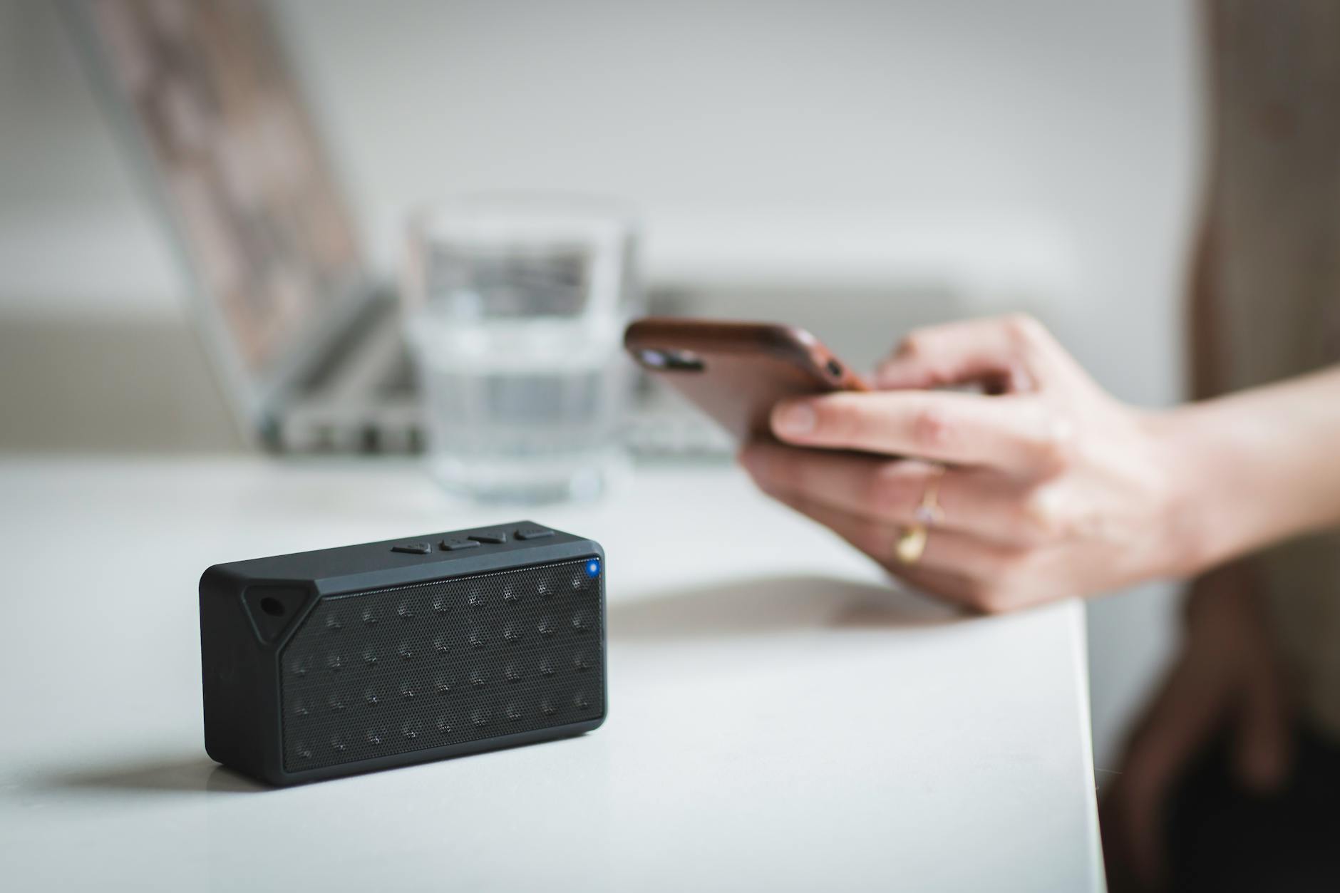 person holding iphone beside black portable speaker